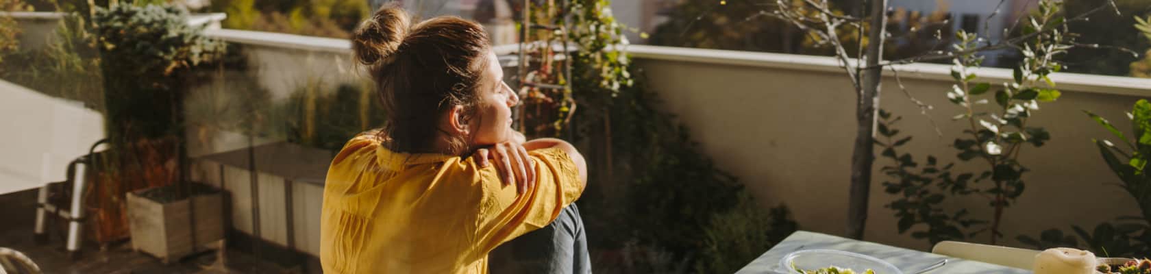 Frau genießt die Sonne auf ihrem Balkon.