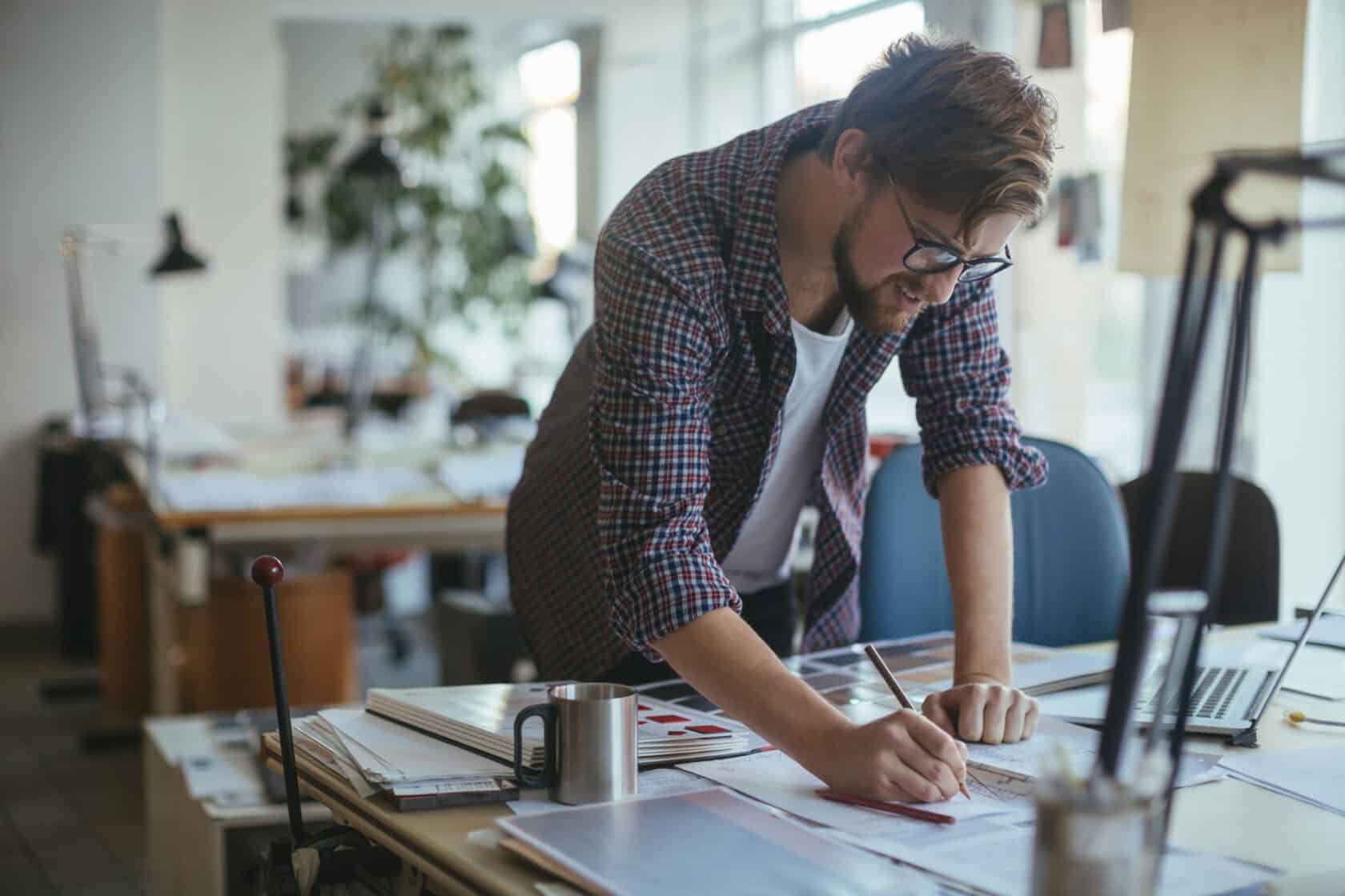 Mann mit Arbeitsmaterialien auf dem Schreibtisch