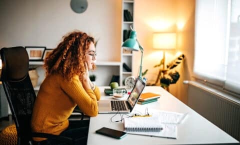 Eine junge Frau schaut konzentriert auf einen Laptop