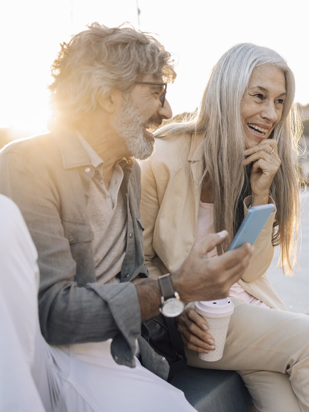 Älteres Paar lachend in der Sonne mit Smartphone